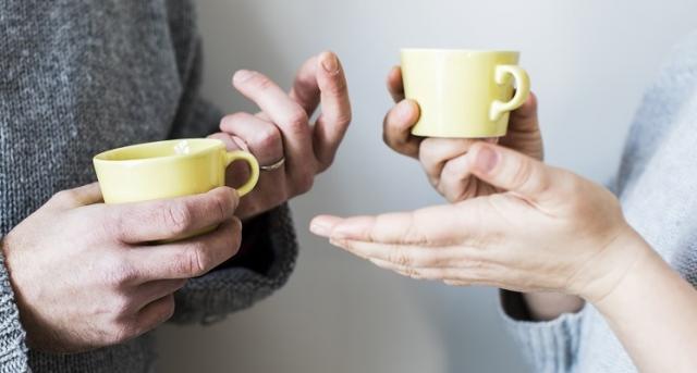 Händer med kaffekoppar, två personer som samtalar.