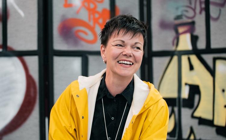 En glad projektledare, Annette Kronholm, i gul regnrock