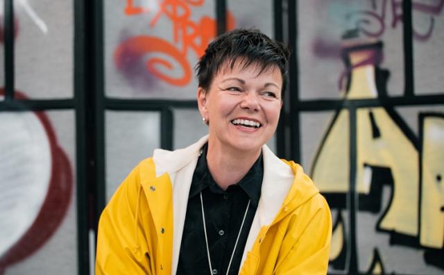 En glad projektledare, Annette Kronholm, i gul regnrock