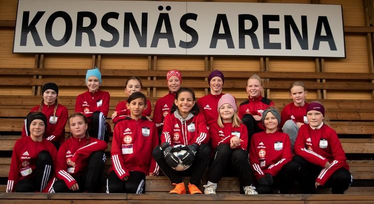 Vinnande laget på en läktare iklädda röda speldräkter. Ovanför dem står det KORSNÄS ARENA på en skylt.