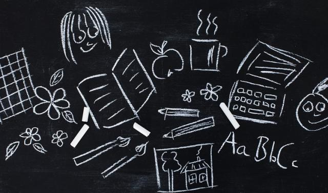 En gammaldags svart tavla med kritritade bilder och bokstäver.