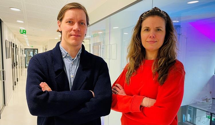 Matias Österberg i blått och Emilia Christiansen i rött står i korridoren utanför Sydkustens kontor, båda med armarna i kors.